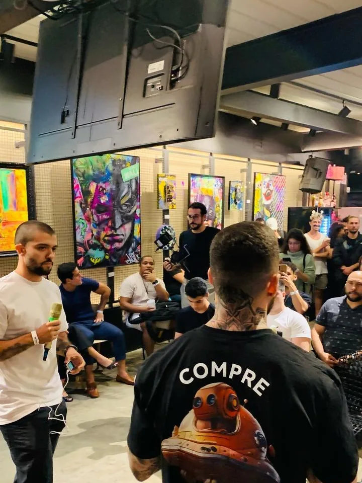 Roda de conversa num evento, em primeiro plano uma camiseta com a estampa Compre Bitcoin com Alfred